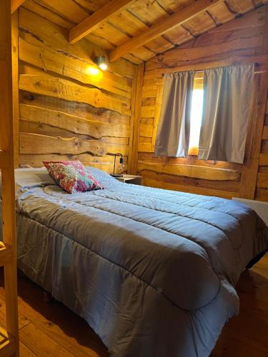 a bedroom with a bed in a log cabin at Guanumby Cabañas in Tandil