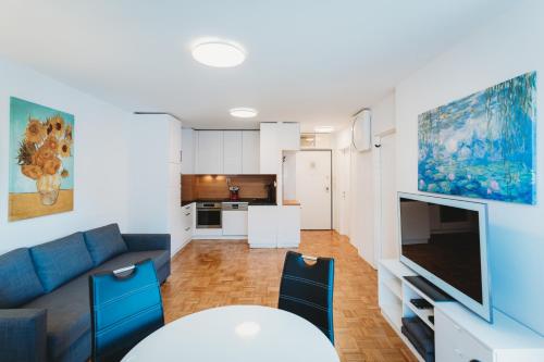 a living room with a blue couch and a tv at Peaceful Little Retreat, spacious free garage park in Ljubljana