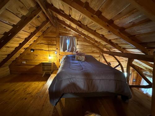 a large bed in a wooden attic room at Guanumby Cabañas in Tandil