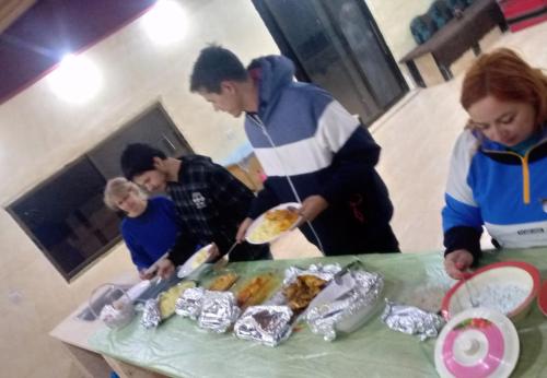 un grupo de personas de pie alrededor de una mesa con comida en Talal Wadi Rum en Wadi Rum