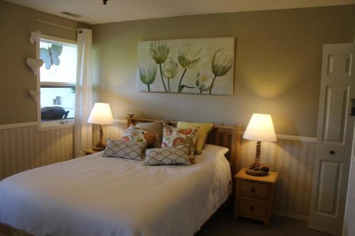 a bedroom with a bed with two lamps and a window at Country Cottage B&B in Vernon