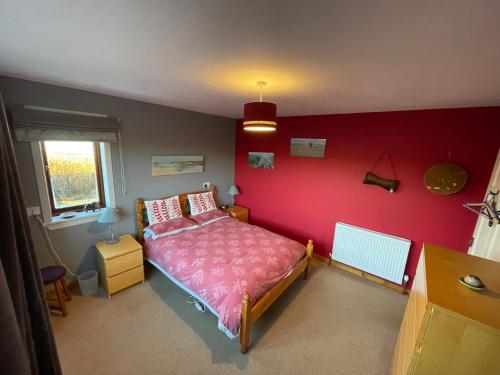 a bedroom with a red wall with a bed at Kisumu in Orkney