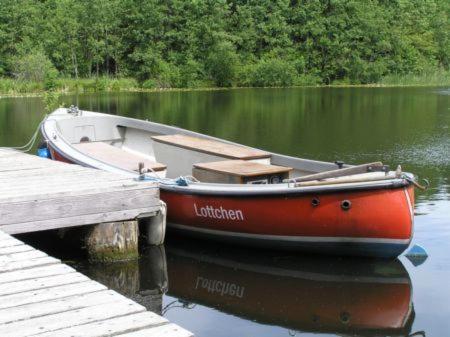 a red boat is docked at a dock at Landhotel Cafe Prälank in Neustrelitz