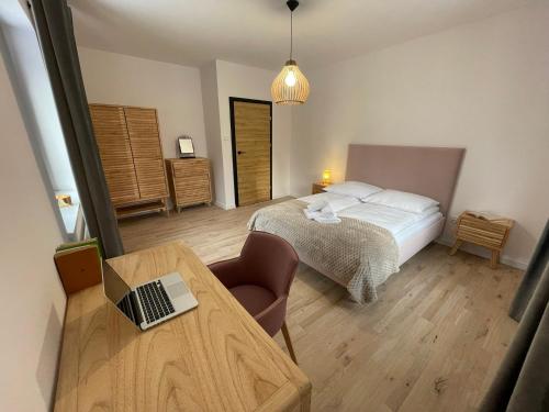 a bedroom with a bed and a desk with a laptop at Dom na Słowiańskiej in Szczawno-Zdrój
