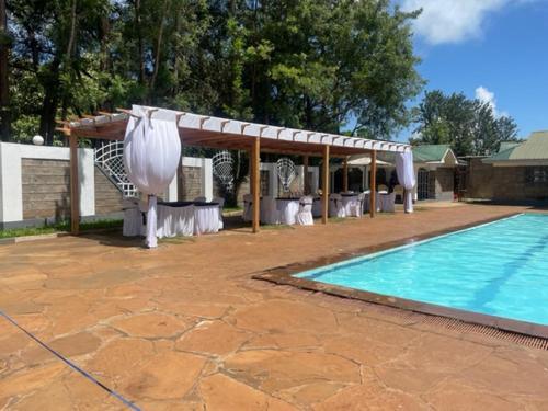 a swimming pool with a pavilion next to a house at Jungle Green Resort, Kiutine in Meru