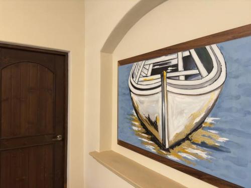 a painting of a boat on a wall next to a door at Loft cuatro. Frente a plaza. in Loreto