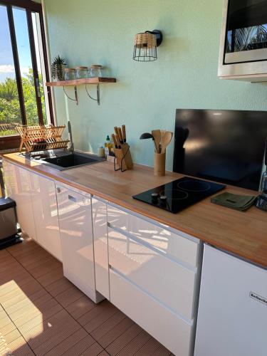 uma cozinha com armários brancos e um balcão de madeira em Studio Karaïbes em Sainte-Anne