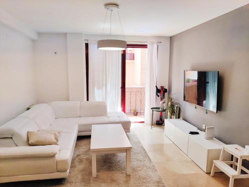 a living room with a white couch and a table at Apartamento, piscina y parking Granada Tico Medina in Granada