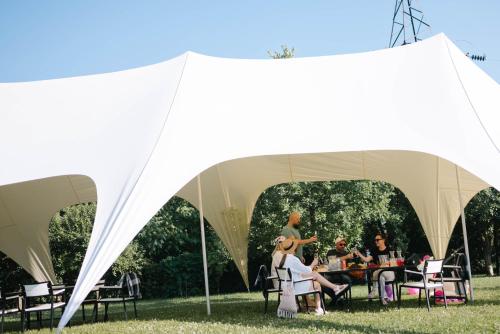 um grupo de pessoas sentadas numa mesa numa tenda em Rodynnyi Maietok Family Estate em Kamianets-Podilskyi