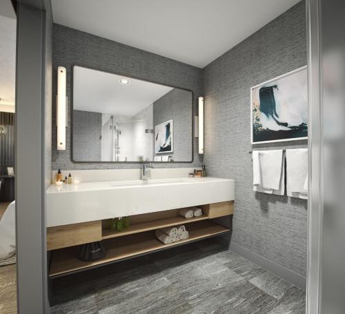 a bathroom with a sink and a large mirror at Maui Coast Hotel in Kihei