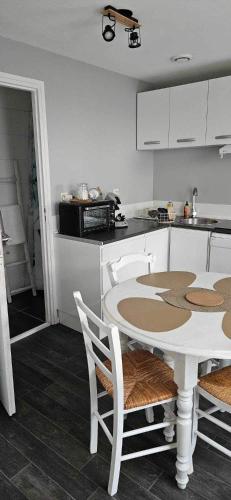une cuisine blanche avec une table et des chaises dans l'établissement Maisonnette cosy avec extérieur, à Mer