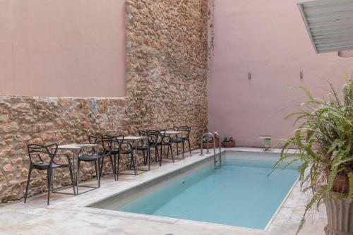 einen Pool mit Stühlen und Tischen neben einer Ziegelwand in der Unterkunft Art Suites Athens in Athen
