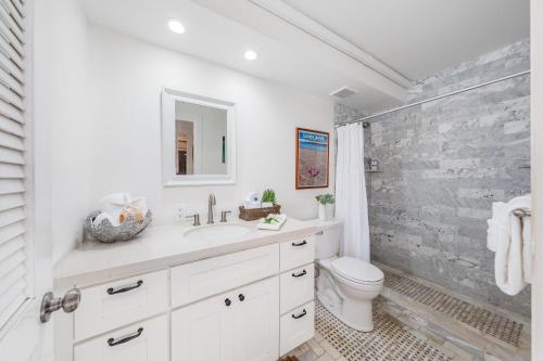 a white bathroom with a sink and a toilet at Lauloa 105 · LOA 105 2BD OceanFront Getaway w AC Pool in Wailuku
