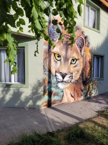 a mural of a lion painted on the side of a building at Hostel Tierra Patagónica in Perito Moreno