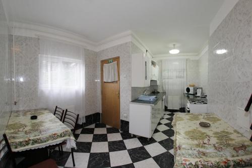 uma cozinha com piso em xadrez e duas mesas em Vila Mura em Buşteni