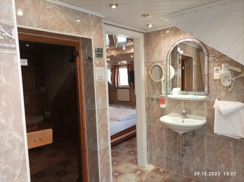 a bathroom with a sink and a mirror and a bed at Central Hotel in Schwetzingen