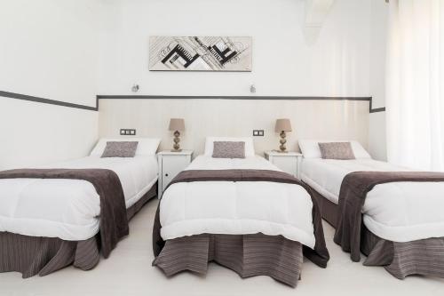 3 camas en una habitación con paredes blancas en Gran Via 63 Rooms, en Madrid