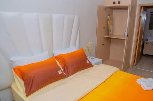 uma cama com almofadas laranja e branca num quarto em La casa de Miah em Sandton
