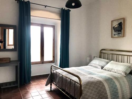a bedroom with a bed with blue curtains and a window at La Almedina casa Bellavista in Cazorla