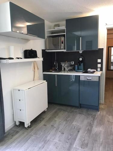 La cuisine est équipée de placards bleus et d'un réfrigérateur blanc. dans l'établissement LES DEUX ALPES, appartement vue imprenable, à Les Deux Alpes