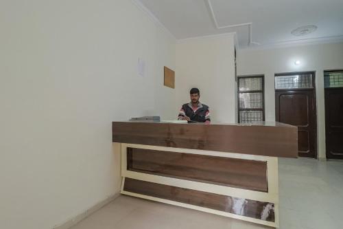 een man aan een balie in een kamer bij OYO Hc Plaza in Kharar