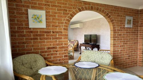 a room with a brick wall and chairs and a table at 3/17 Park Street in Port Macquarie