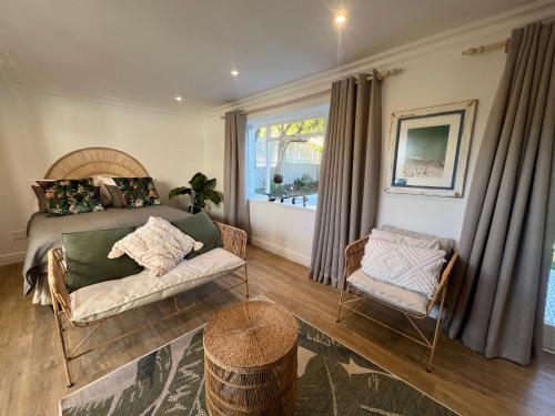 a bedroom with a bed and a couch and a window at Casa Giada Noordhooek Beach in Cape Town