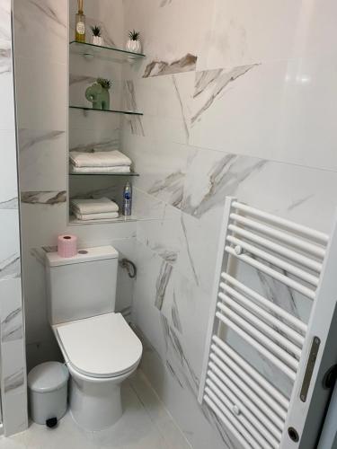 La salle de bains blanche est pourvue de toilettes et d'étagères. dans l'établissement COEUR DE CALVI, à Calvi