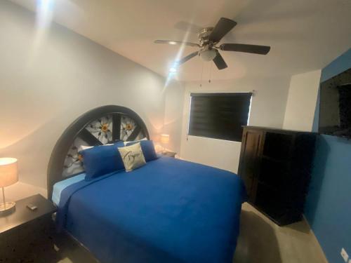 um quarto com uma cama azul e uma ventoinha de tecto em Linda Vista 401 em Puerto Peñasco
