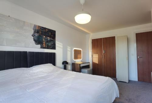 a bedroom with a white bed and a painting on the wall at Celaka Birmingham Central apartment in Birmingham