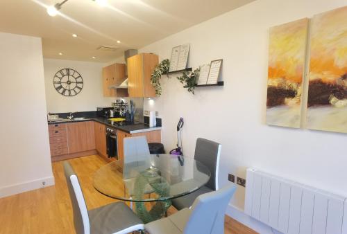 a kitchen with a glass table and some chairs at Celaka Birmingham Central apartment in Birmingham