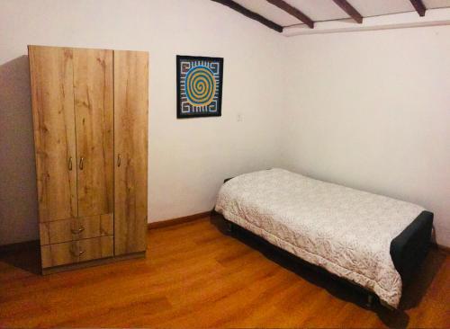 a bedroom with a bed and a wooden cabinet at Alojamiento Cuarto Espiral in Manizales