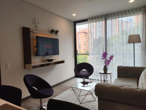 uma sala de estar com um sofá e cadeiras e uma televisão em Tropical Confort suite Poblado welcome breakfast em Medellín