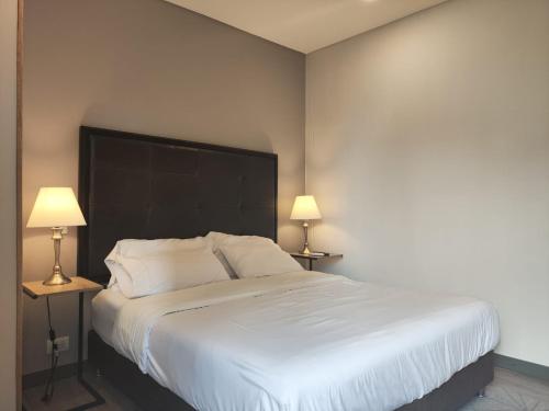 um quarto com uma grande cama branca e 2 candeeiros em Tropical Confort suite Poblado welcome breakfast em Medellín
