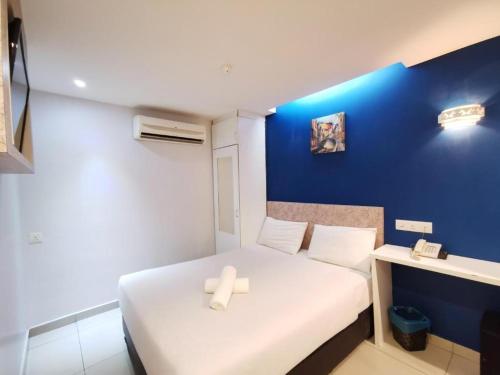 a small room with a bed and a blue wall at Mozu Hotel Sri Hartamas in Kuala Lumpur