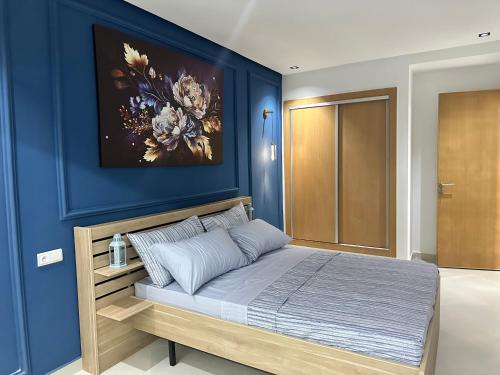 een slaapkamer met een blauwe accentmuur en een bed bij Appartement Bouznika Plage in Bouznika