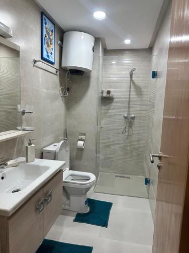 een badkamer met een douche, een toilet en een wastafel bij Appartement Bouznika Plage in Bouznika
