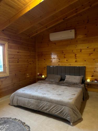 1 dormitorio con 1 cama grande en una habitación de madera en كوخ السعاده happiness hut, en Thuwal