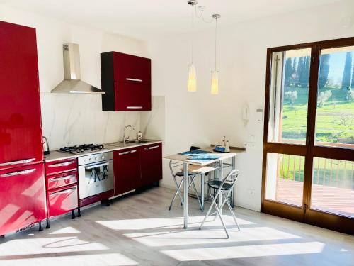een keuken met rode kasten en een tafel en een raam bij Montecatini Sunrise in Montecatini Terme