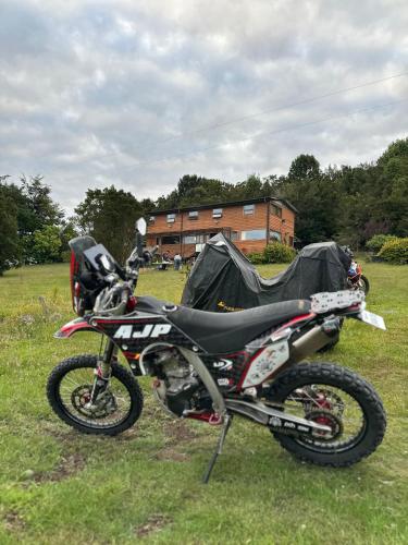 a motorcycle parked in a field with a tent at Hostal Hunter in Puerto Montt