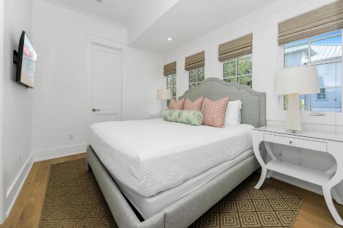 - une chambre blanche avec un grand lit et un bureau dans l'établissement Harp's Haven Carriage House, à Rosemary Beach