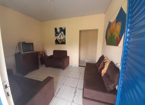 een woonkamer met een bank en een tv bij Sítio no interior de MG, lugar de sossego e paz! in São Domingos do Prata