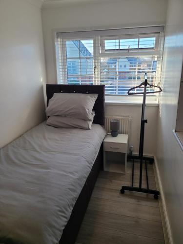 a bedroom with a bed with a lamp and a window at GATWICK SINGLE ROOM. (GR3). West Sussex in Ifield