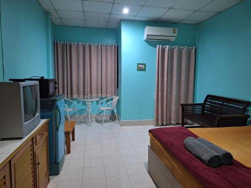 a room with a tv and a table and a couch at Phonsomboon Guesthouse in Koh Tao