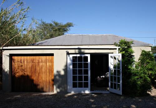 a garage with a door open in front of a house at 1920s Charm on Waveren in Tulbagh