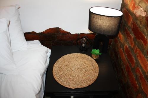 a nightstand with a hat and a lamp on it next to a bed at 1920s Charm on Waveren in Tulbagh