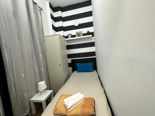a small bedroom with a bed with a striped wall at Fancy Partition Room Near Mashreq Metro / SZ Road in Dubai