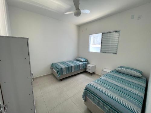 een slaapkamer met 2 bedden en een plafondventilator bij Casa nova e móveis novos in Caraguatatuba