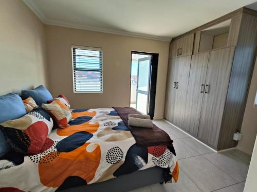 a bedroom with a large bed with colorful pillows at Frank's Place in Yzerfontein