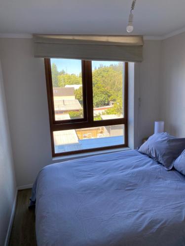 een slaapkamer met een bed en een groot raam bij Departamento en San Pedro de la Paz. in San Pedro de la Paz